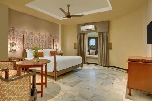 a bedroom with a bed and a table in a room at The Fern Bambora Fort Udaipur, Bambora, Series by Marriott in Udaipur