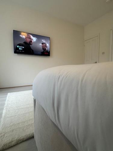 une chambre avec un lit et une télévision au mur dans l'établissement The Beige House, à Batley