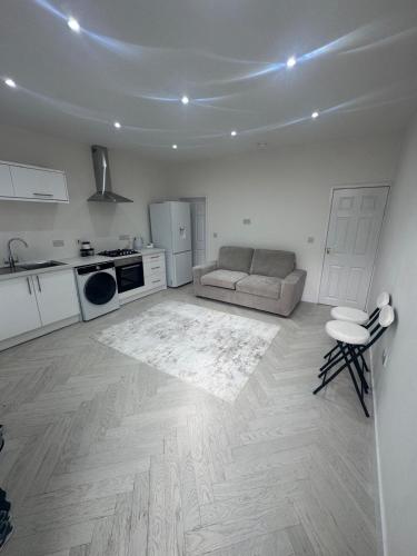 a white living room with a couch and a kitchen at The Beige House in Batley