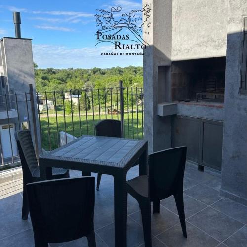 een tafel en stoelen op een balkon met een bord bij cabañas RIALTO in Villa Amancay