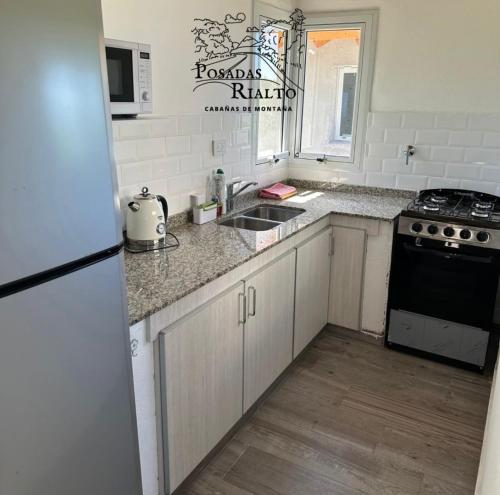 een keuken met een spoelbak, een fornuis en een koelkast bij cabañas RIALTO in Villa Amancay