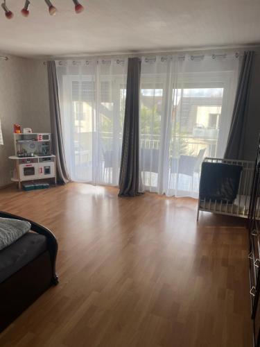 een woonkamer met een houten vloer en glazen schuifdeuren bij Sunshine FeWo in Rust