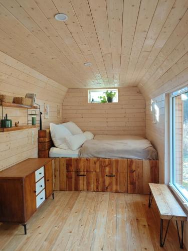 a bed in a small room with a wooden ceiling at Tiny House am Waldrand in Heideblick