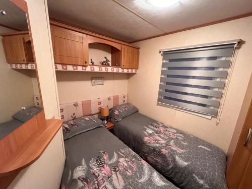 a small room with two beds and a window at A and C Coastal Hideaway Private Decking in Colchester