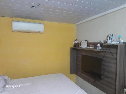 a bedroom with a tv and a yellow wall at Casa para alugar para o Carnaval in Recife