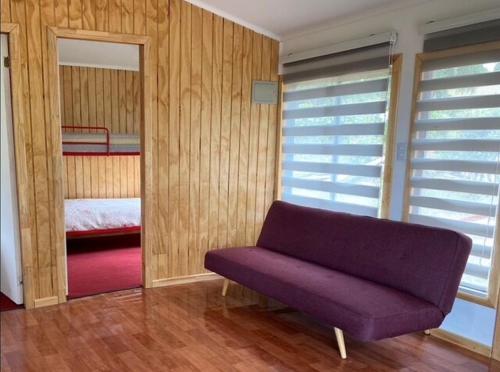 a living room with a purple couch and a bedroom at Cabaña Lago Ranco in Ranco