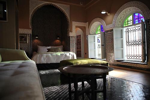 a bedroom with two beds and a table and windows at L'Alcazar in Rabat