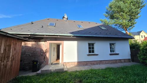 a small white house with a black roof at Popelucha in Lomnice nad Popelkou