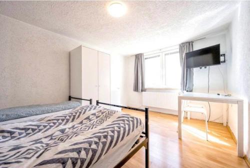 een slaapkamer met een bed, een bureau en een televisie bij Nest-Unterkunft in Bad Überkingen