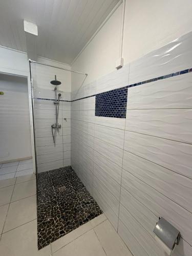 a bathroom with a shower with a black and white tiles at Villa JOSAMY Charmante Villa avec Piscine à Deux Pas de la Mer in Sainte-Luce
