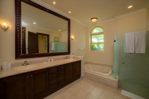 een badkamer met 2 wastafels, een douche en een spiegel bij Bella Vista 3F 3 bdr beach club view in Los Suenos in Herradura