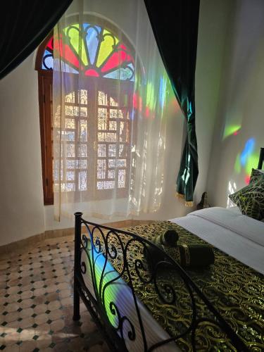 a bedroom with a bed with a stained glass window at Chambres Émeraude et Rubis - Riad Lotus Bleu in Fès