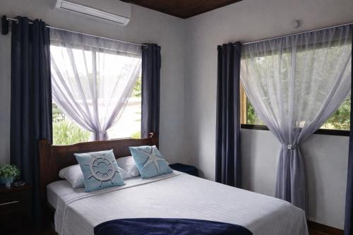 ein Schlafzimmer mit einem Bett mit blauen Kissen und einem Fenster in der Unterkunft Villa Marina, Nosara in Nosara