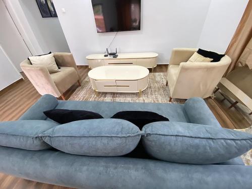 ein Wohnzimmer mit einem blauen Sofa und Stühlen in der Unterkunft Maculusso City Stay in Luanda