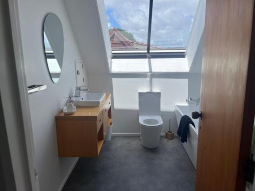 une salle de bain avec un lavabo et des toilettes et une fenêtre dans l'établissement The Lighthouse - Stunning Sun Filled Home, à Tauranga