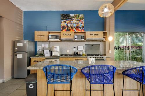 une cuisine avec des chaises bleues et un comptoir avec un comptoir. dans l'établissement Colmena Hotel CDMX Tonala, à Mexico