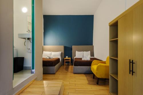 Cette chambre comprend deux lits et une chaise jaune. dans l'établissement Colmena Hotel CDMX Tonala, à Mexico