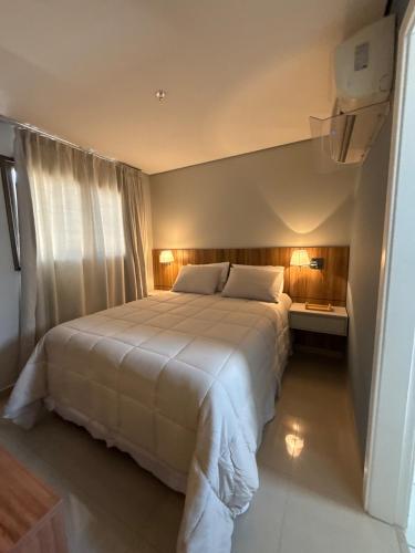 a bedroom with a large white bed with two lamps at Flat completo e confortável in Cuiabá
