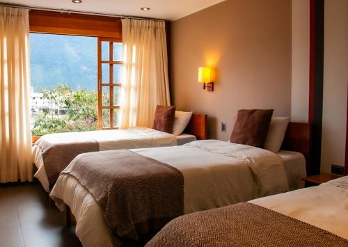 een hotelkamer met 3 bedden en een raam bij Hotel Heidinger in Oxapampa
