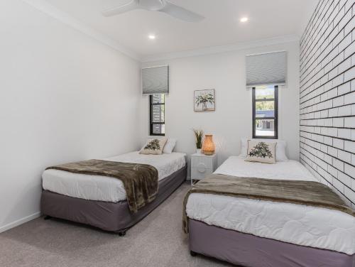 2 Betten in einem Zimmer mit weißen Wänden und Fenstern in der Unterkunft Ultimate Beachside Haven in Cabarita - Pet Friendly in Cabarita Beach