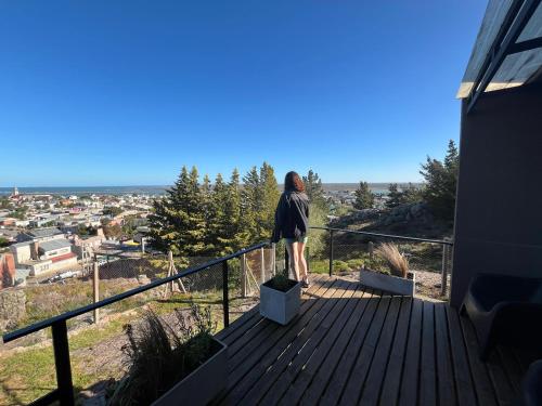 een vrouw staat op een terras en kijkt uit over een stad bij HOMU DEP - Vista al mar in Puerto Deseado