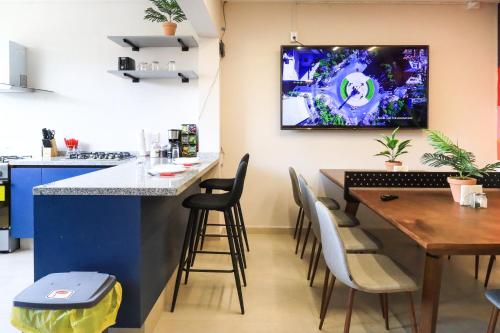 a kitchen with a table and a tv on the wall at Colmena Hotel CDMX Suites Roma in Mexico City