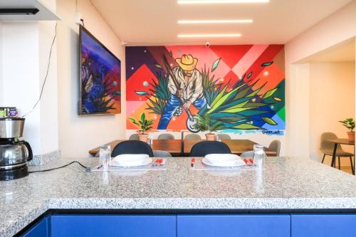 a kitchen with a counter with chairs and a painting at Colmena Hotel CDMX Suites Roma in Mexico City