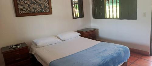 een kleine slaapkamer met een bed en twee ramen bij Finca Hotel El Juncal in Venecia