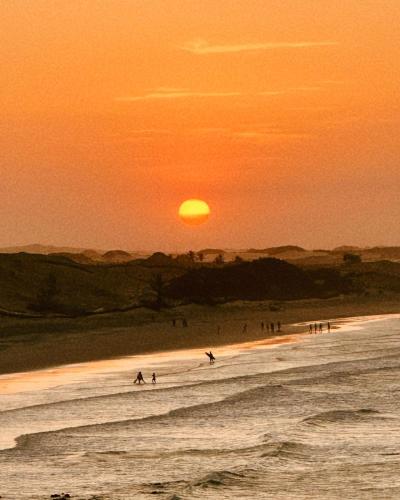 a group of people surfing on the beach at sunset at Casa Vento Curimãs in Barroquinha