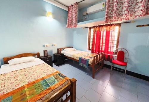 a bedroom with two beds and a red chair at Saralalayam in Varkala