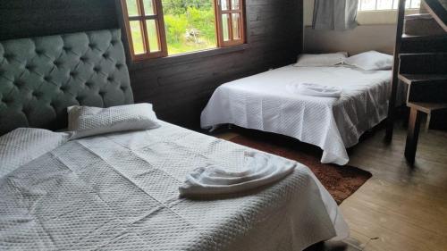 een slaapkamer met twee bedden en twee ramen bij Chalé com Piscina Aquecida - Vista Panorâmica da Praia, a 200m do Mar, Sala de Jogos, Academia e Churrasqueira in Imbituba