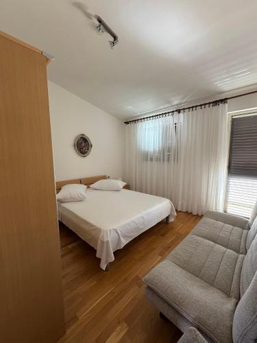 a bedroom with a white bed and a couch at Apartments by the sea Prizba, Korcula - 149 in Prizba