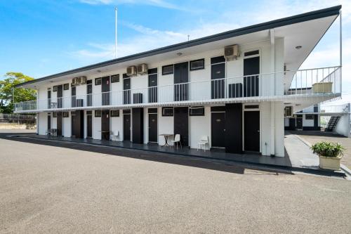 a large white building with tables and chairs in a parking lot at Kingsway Motel Geelong in Geelong