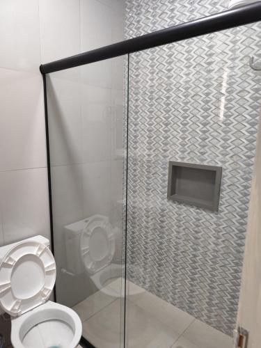 a bathroom with a toilet and a glass shower stall at Apartamento central - Feijó 01 in Vitória da Conquista