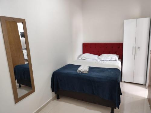 a bedroom with a bed with a red headboard and a mirror at Apartamento central - Feijó 01 in Vitória da Conquista