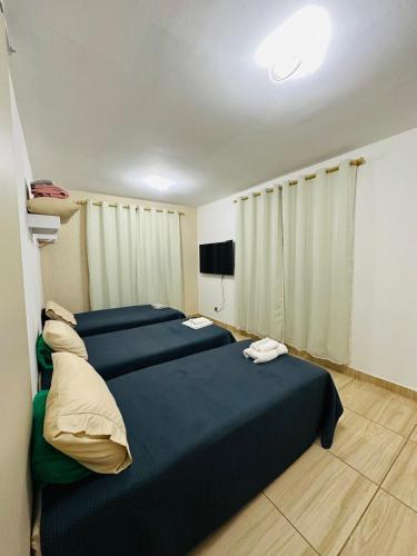 a room with three beds and a flat screen tv at Apartamento 4 quartos Contagem in Contagem