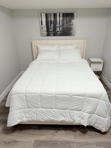 een groot wit bed in een witte slaapkamer bij True Haven Deluxe in Prince George