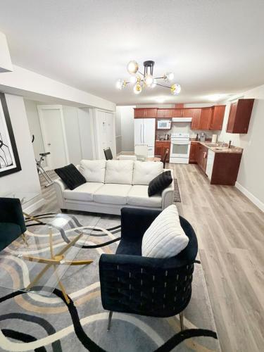 a living room with a white couch and chairs at True Haven Deluxe in Prince George