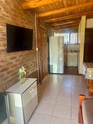 a living room with a tv on a brick wall at Departamento Río Blanco - muy cerca del Lago Lezana in Cholila