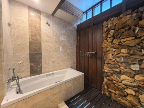 a bathroom with a tub and a stone wall at Langkawi Lagoon Floating Resort 02 in Langkawi Intl