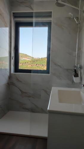 a white bathroom with a window and a sink at Casa da Corredoura in Santa Marta de Penaguião