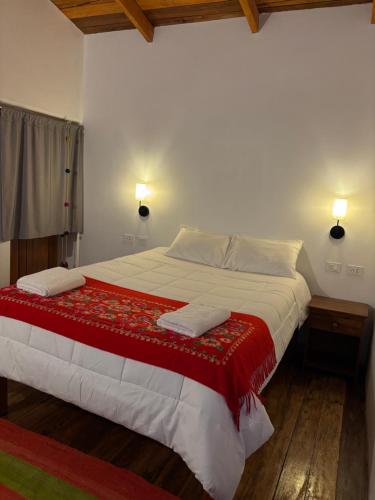a bedroom with a large bed with a red and white blanket at Lavanda lodge Ollantaytambo in Ollantaytambo