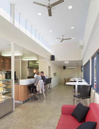 two people sitting at a table in a room at Frangipanis at Footprints in Preston Beach