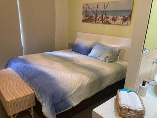 a bedroom with a bed with blue pillows at Frangipanis at Footprints in Preston Beach