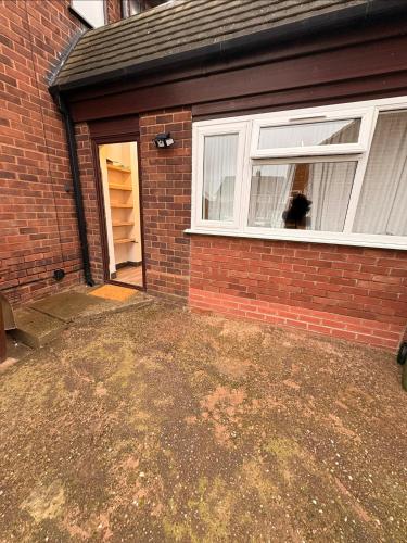 a dog looking out the window of a brick house at Cozy living in Great Barr Birmingham in Holly Lane