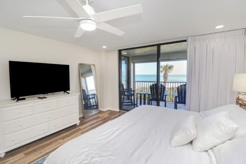 een witte slaapkamer met een groot bed en een flatscreen-tv bij Sand Dollar 1-202 in St. Augustine