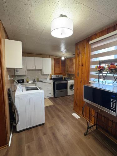 a kitchen with white cabinets and wooden floors at Cozy 3BR House Near Airport & Transit! in Mississauga