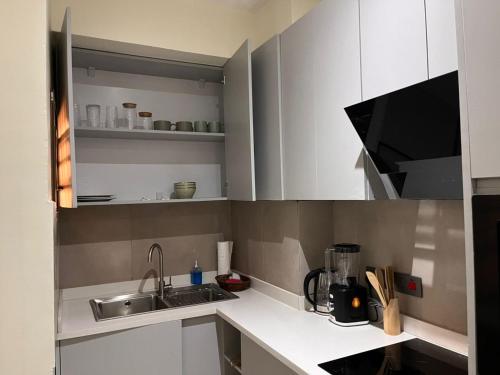 a small kitchen with white cabinets and a sink at The Veron, Dzorwulu in Lapaz