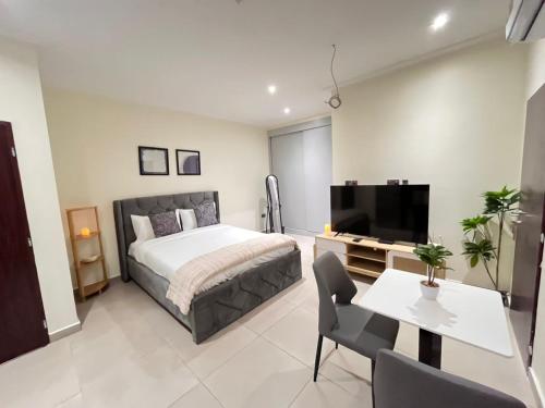 a bedroom with a bed and a tv and a table at The Veron, Dzorwulu in Lapaz