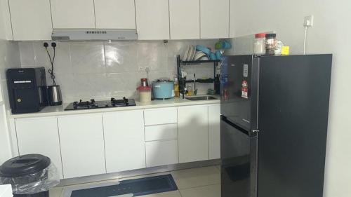 een keuken met witte kasten en een zwarte koelkast bij Lylinz sierra heights in Pasir Gudang